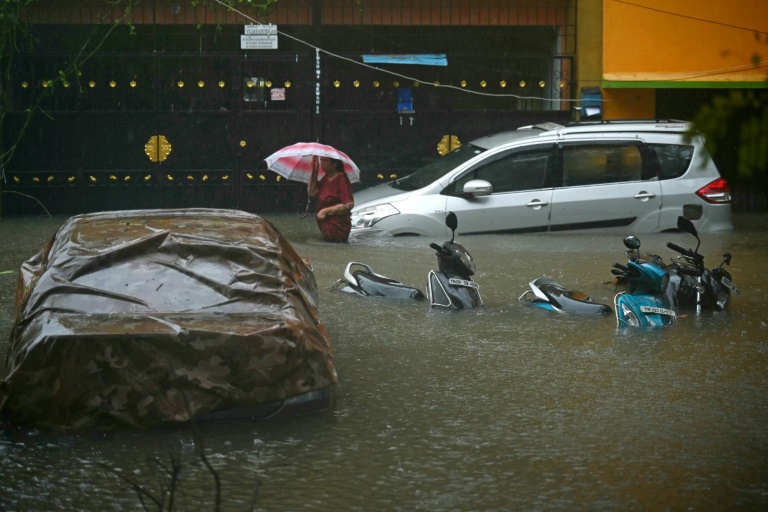 A resident wades through a flooded street after heavy rains in Chennai on December 4 (R. Satish BABU)