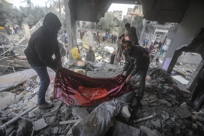 Palestinians transport the body of a victim found under the rubble of destroyed buildings after heavy Israeli bombardment of the Al-Maghazi camp in the central Gaza Strip. The Hamas-controlled Ministry of Health said more than 70 people were killed. Mohammed Talatene/dpa