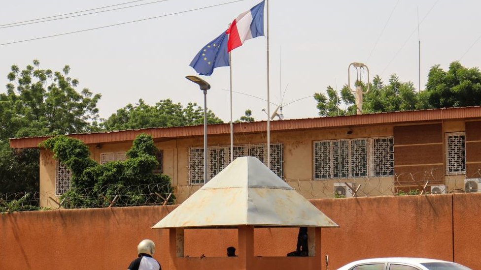 Motorists drive past as the French and European flags fly atop the French embassy compound, in Niamey, Niger, 28 August 2023.