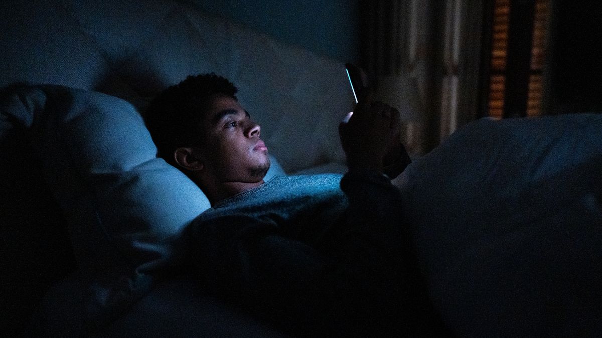 Man in bed looking at a generic phone